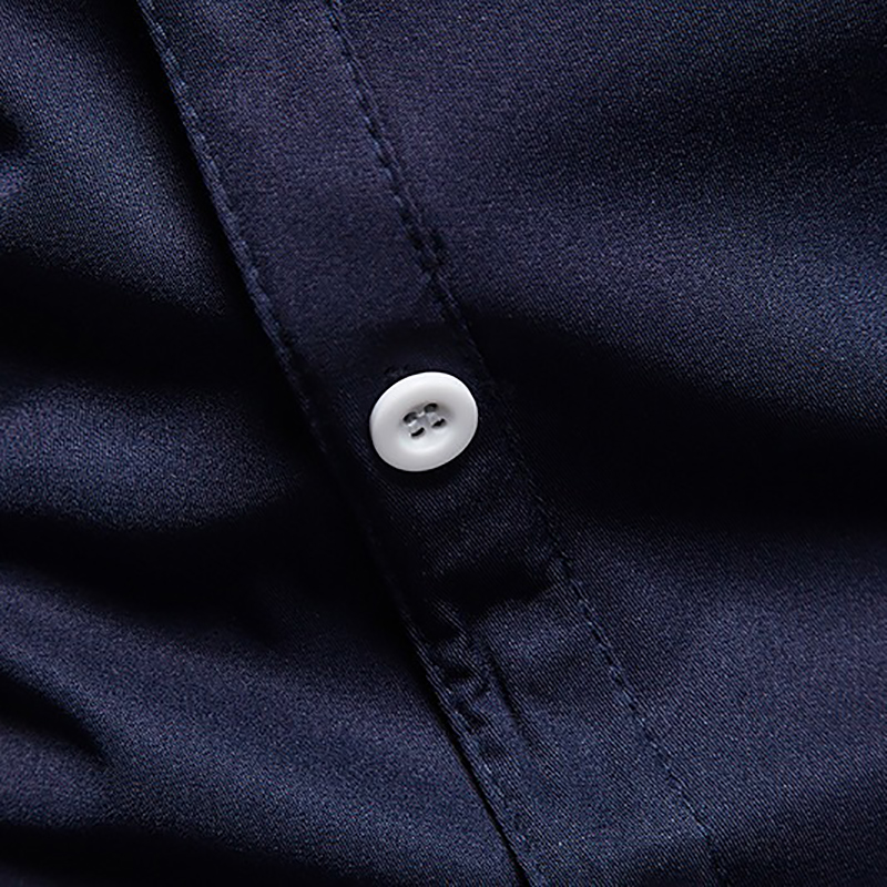 Close-up of a button on a men's asymmetric cotton shirt in navy blue, highlighting quality and design.