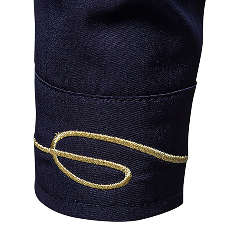 Detail of the embroidered golden design on the cuff of a men's asymmetric long-sleeved shirt.