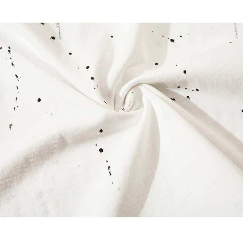 Close-up of white fabric with black ink splatters, showcasing the trendy punk style of the men's sweatshirt.