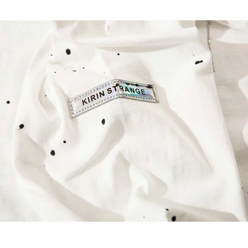 Close-up of white punk-style sweatshirt fabric featuring KIRIN STRANGE label and artistic black ink splatters.