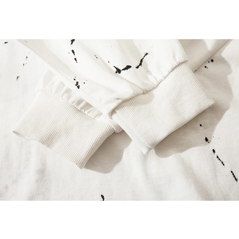 Close-up of the cuffs of a white men's punk sweatshirt with trendy black ink splatter pattern.