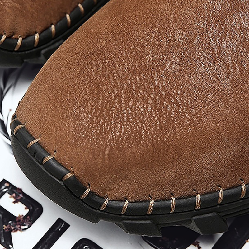 Close-up of men's soft genuine leather boots with detailed stitching and rubber sole in brown color.