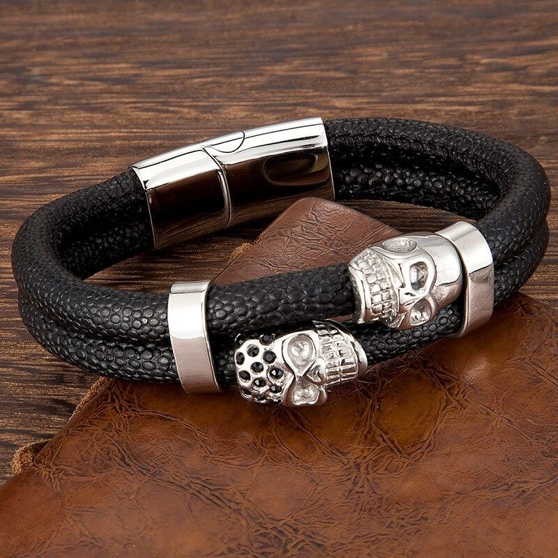 Men's punk style leather bracelet with skull magnetic clasp on a wooden background.