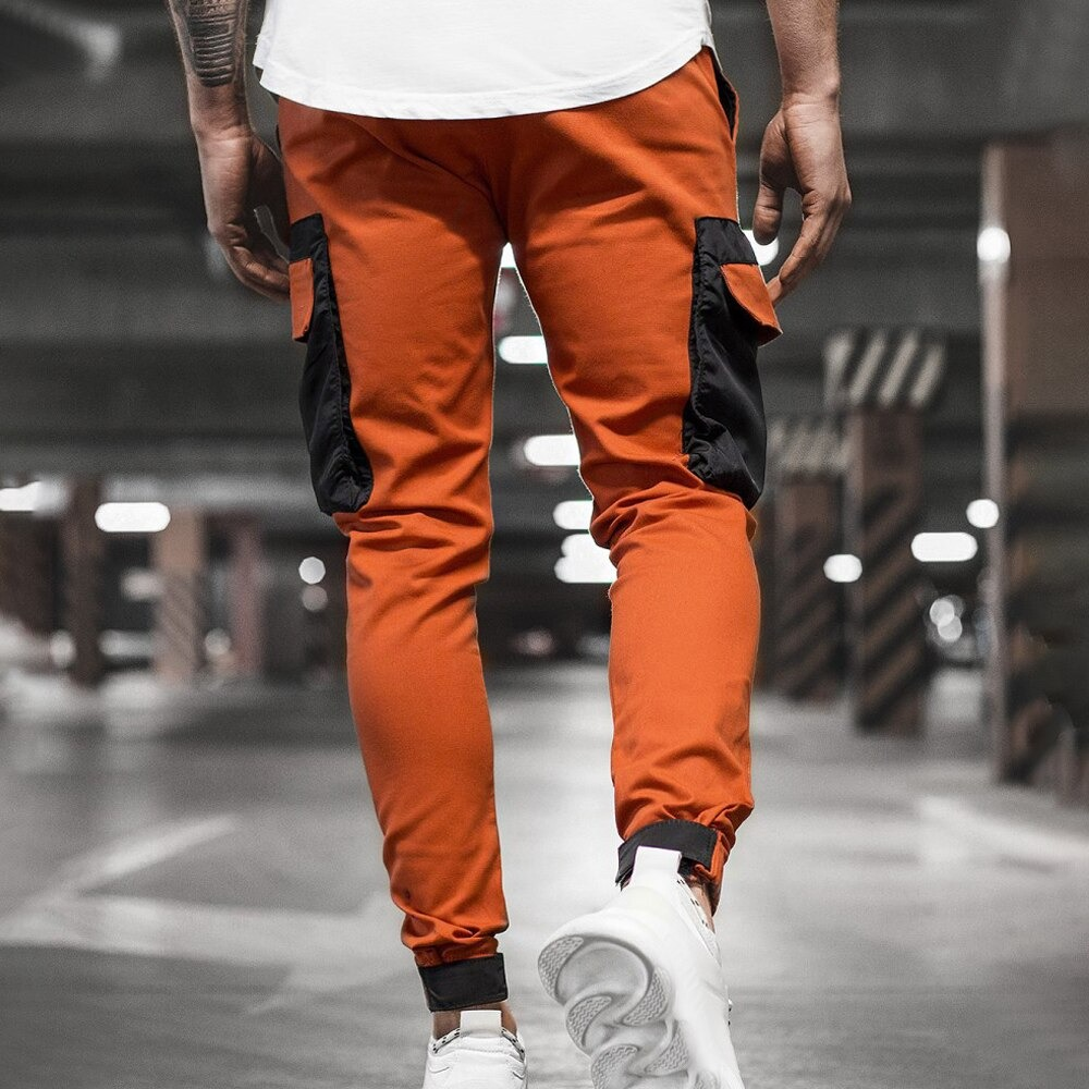 Stylish men's joggers pants in orange with black patch pockets, perfect for casual streetwear outfits.