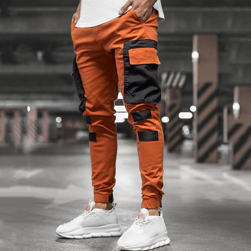Men's streetwear jogger pants in orange with black patch pockets, perfect for casual outings and sporty looks.