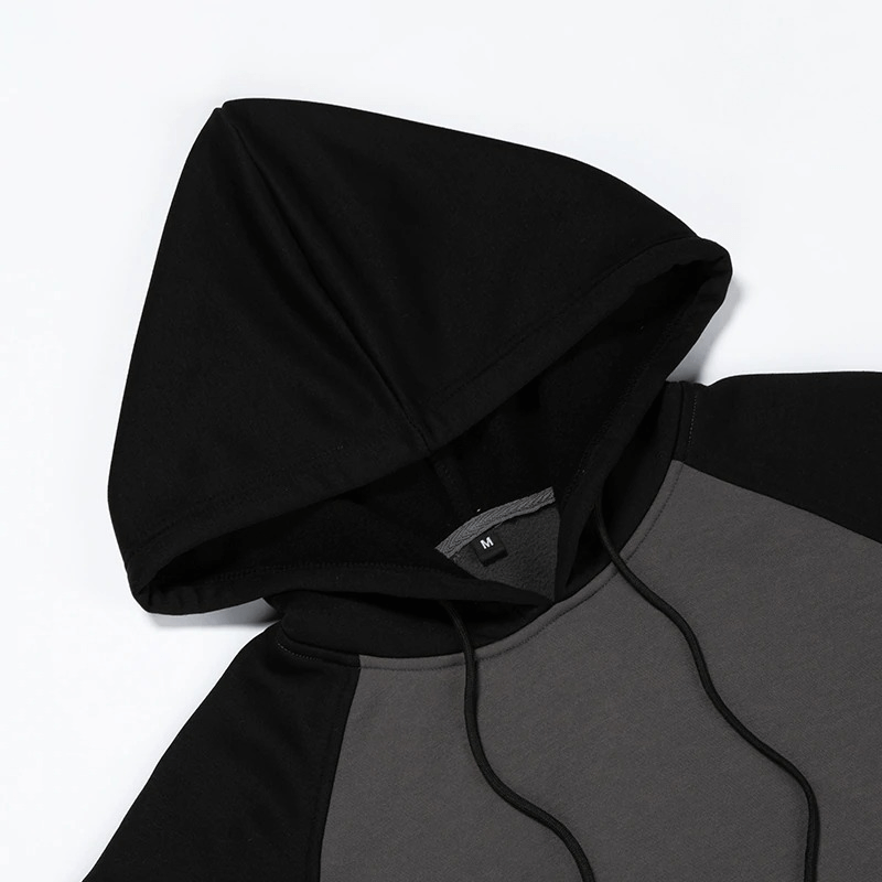 Close-up of a men's patchwork fleece hoodie featuring a black hood and gray body, perfect for alternative style outfits.