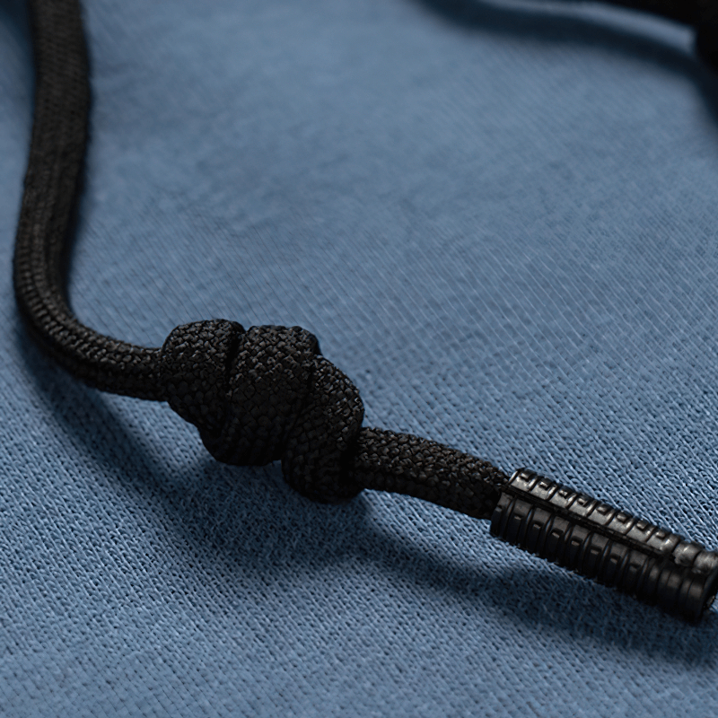 Close-up of a knotted black drawstring on a blue hoodie, showcasing its stylish design and functionality.