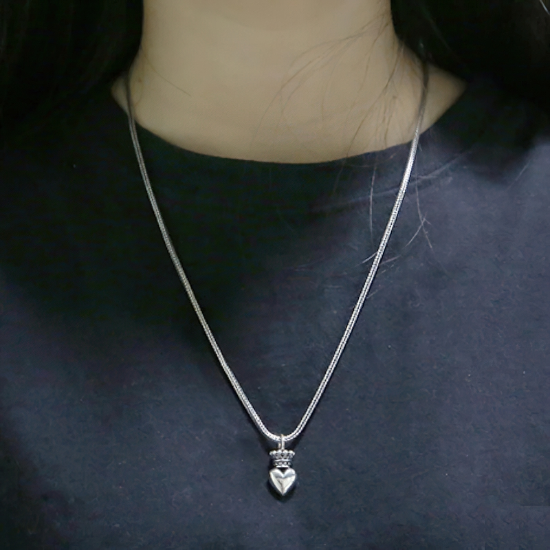 Sterling silver crowned heart pendant necklace on a woman, showcasing stylish casual jewelry.