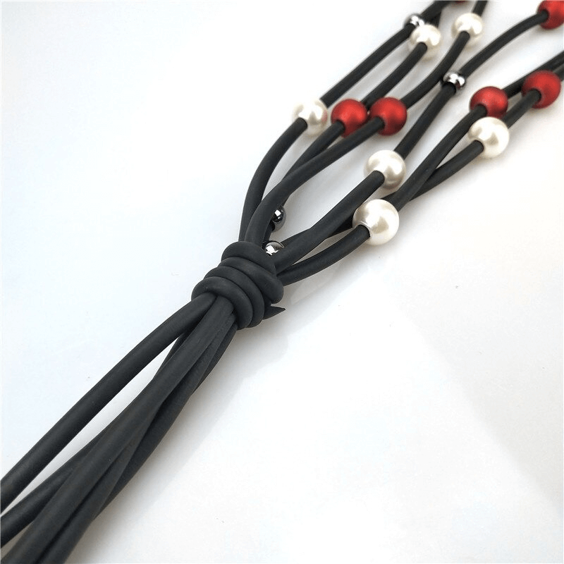 Handmade long necklace featuring red and white pearls on black rubber for a stylish luxury look.