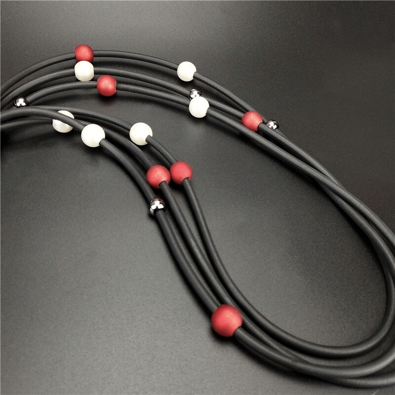 Stylish red and white pearls long necklace on black background, perfect luxury accessory for casual outfits.