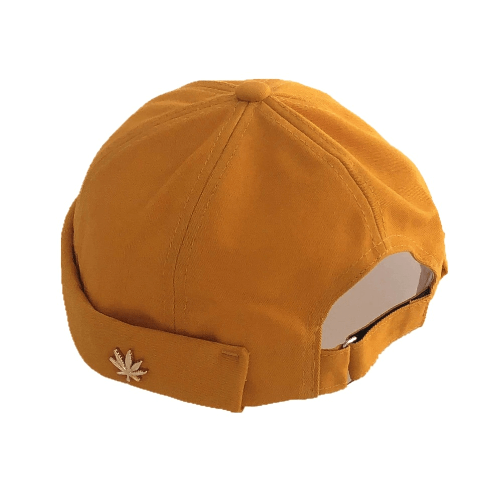 Fashionable mustard brimsless cap with leaf rivet, adjustable cotton skullcap for alternative style outfits.