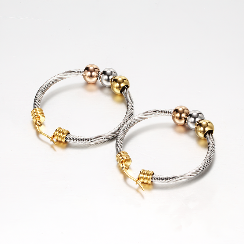 Trendy silver and gold stainless steel earrings with twisted design and decorative beads, perfect for elegant outfits.