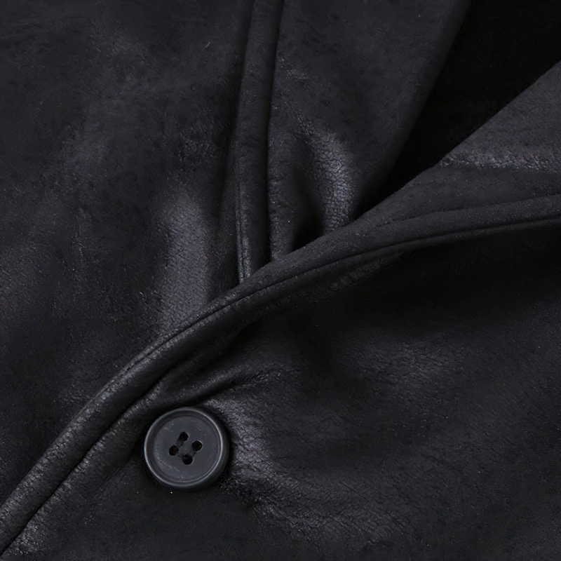Close-up of a black suede vest's fabric and stylish button, showcasing steampunk fashion details.