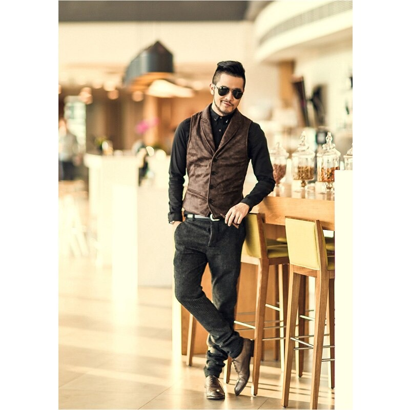 Stylish man in a brown suede steampunk vest, exuding elegance and confidence in a modern setting.