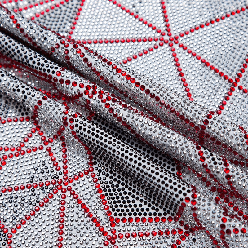 Close-up of silver fabric adorned with red and black rhinestones, showcasing shimmering patterns perfect for alternative fashion.