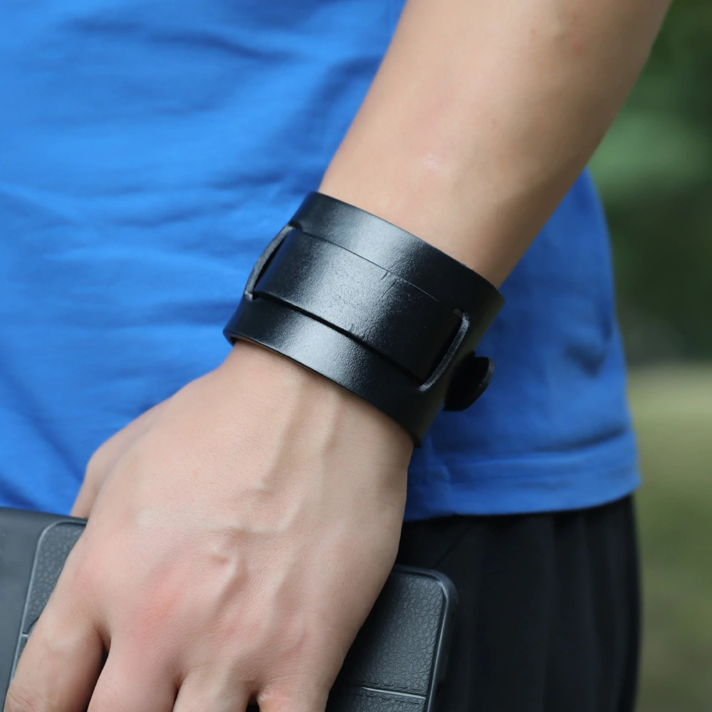 Wide black genuine leather cuff bracelet on a wrist, perfect for punk style and vintage jewelry lovers.