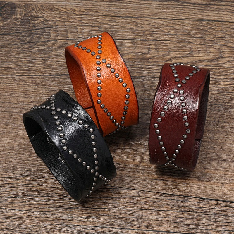Three wide leather bracelets in black, brown, and orange with silver rivets, showcasing punk rock style for unisex fashion.