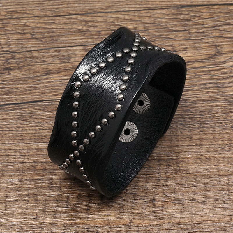 Wide black leather bracelet with silver rivets, perfect for punk-rock style and unisex fashion.