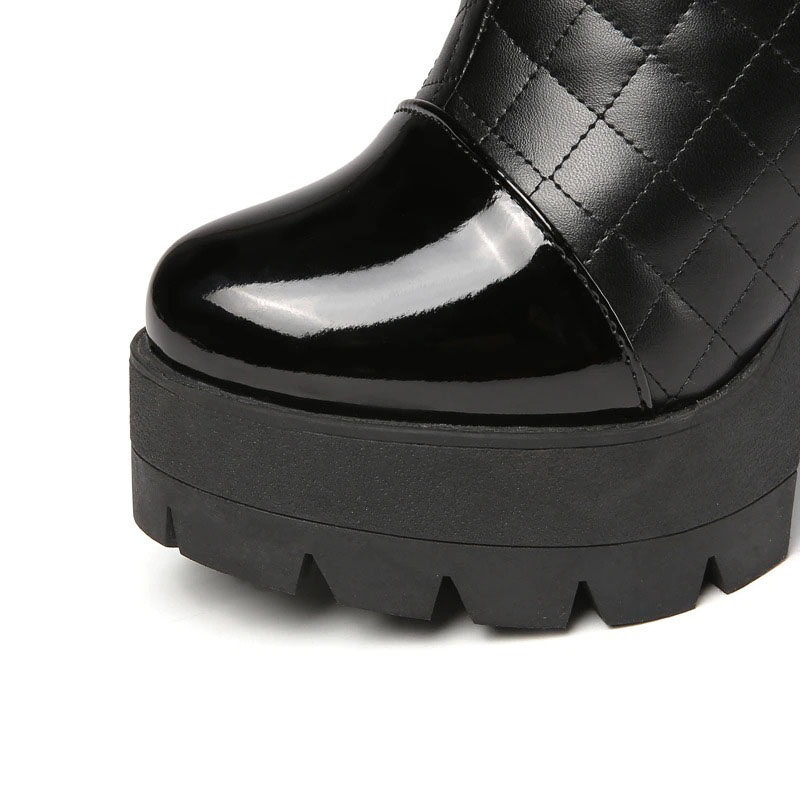 Close-up of stylish women's high heel knee high boot in glossy black PU leather with chunky sole.