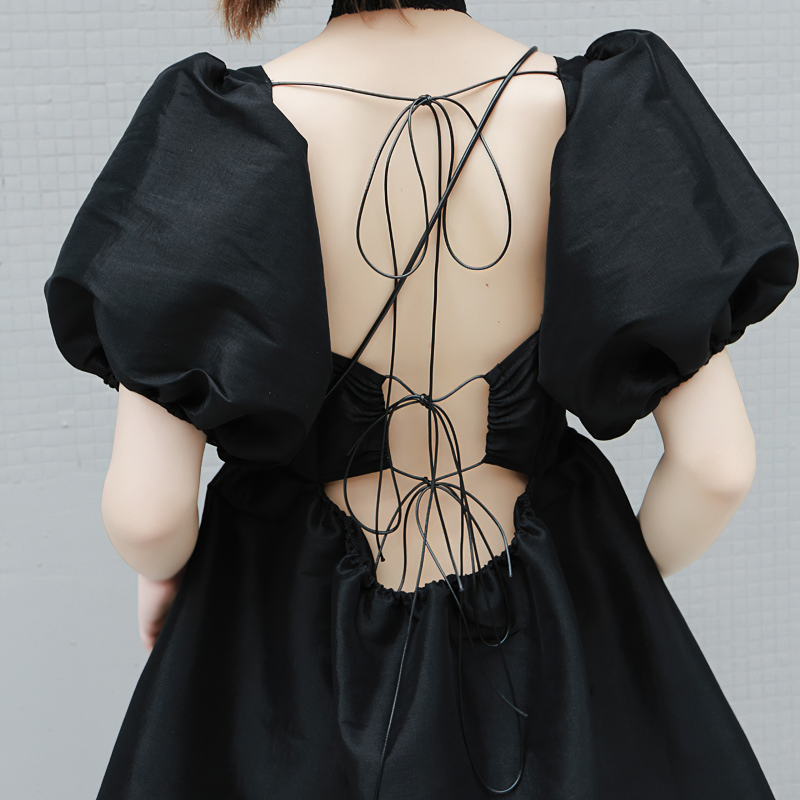Back view of a fashion women's black dress with puffy short sleeves and lace-up detail, ideal for gothic style lovers.
