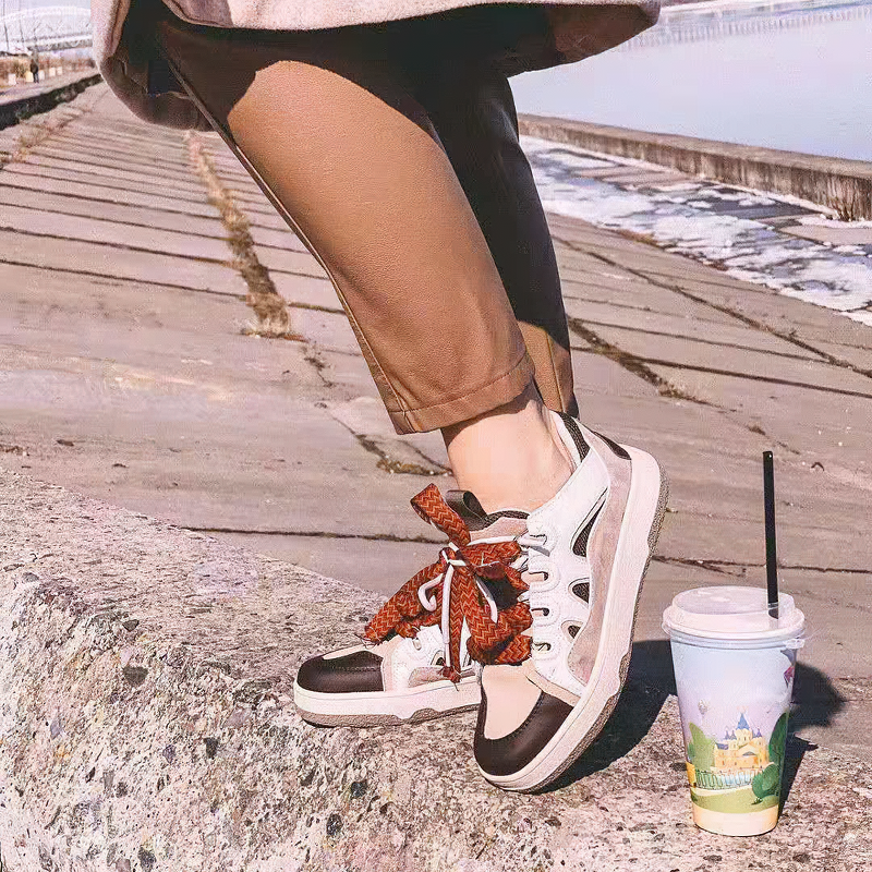 Fashion women's chunky platform sneakers with mixed colors on a sunny day by the water, paired with stylish pants.