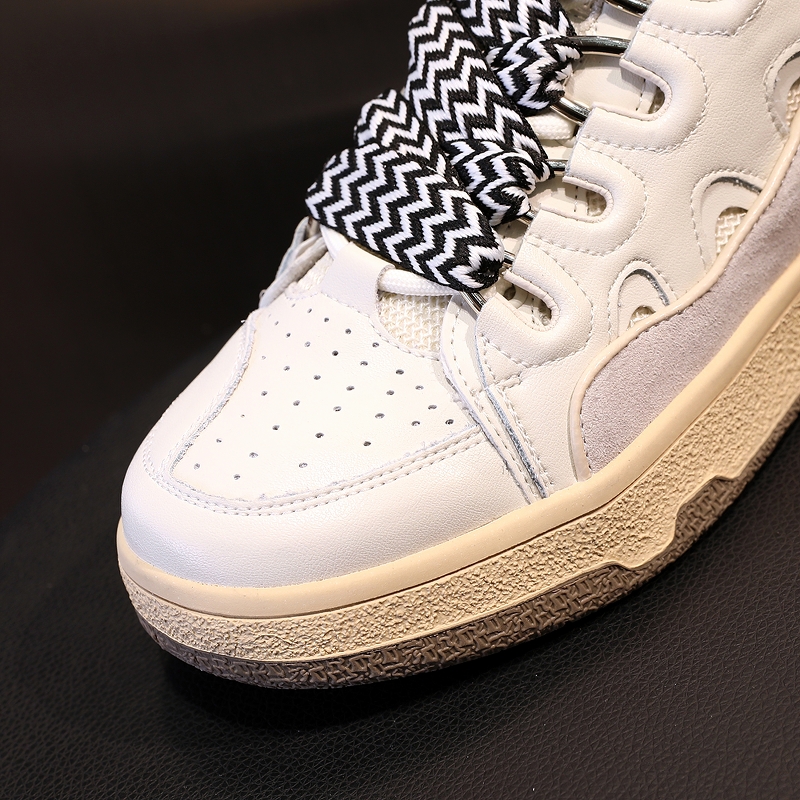Close-up of women's chunky platform sneaker with retro design, mixed colors, and unique black and white striped laces.