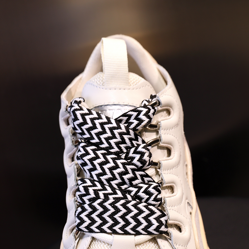Chunky platform sneaker with unique black and white zigzag laces, showcasing retro genuine leather style.