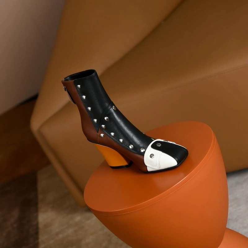 Fashion women's genuine leather ankle boot with rivets and high heel, multicolour design displayed on a stylish table.