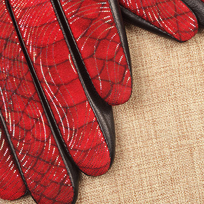 Red leather gloves with a spider web design on a beige background, perfect for stylish warmth.