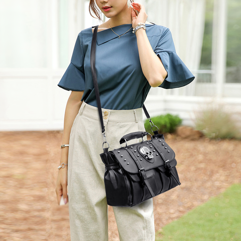 Fashionable woman carrying a cool black PU leather handbag with rivets and skull detail in a trendy outfit.