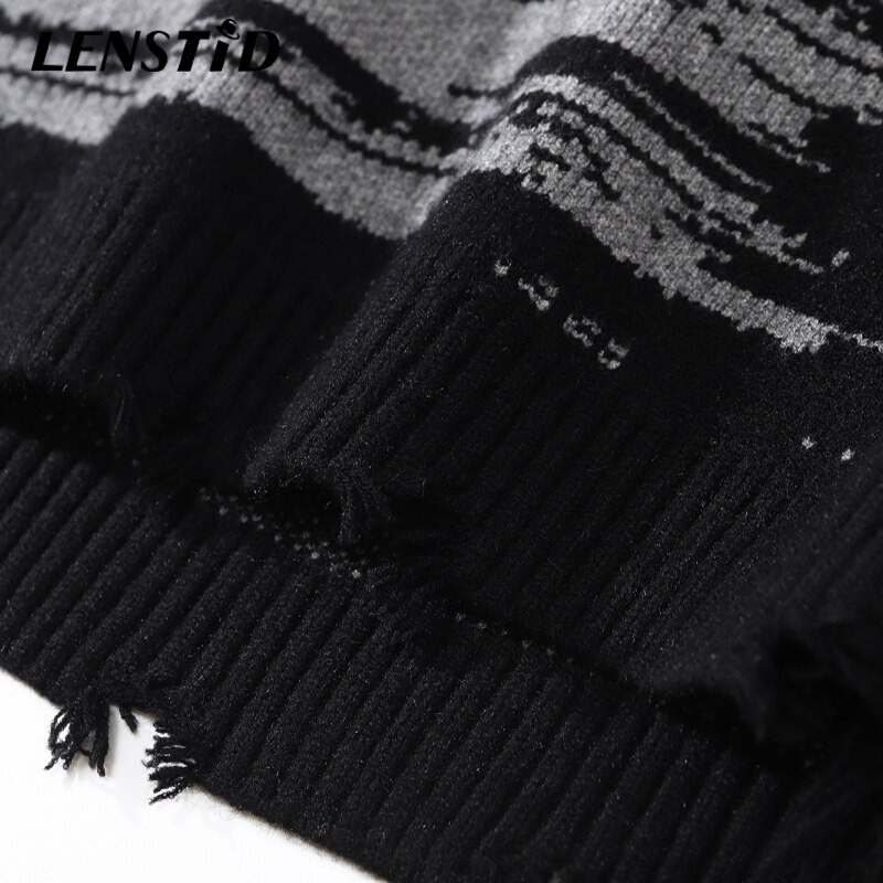 Close-up of a black knitted oversized sweater featuring gray patterns and a stylish frayed hem.