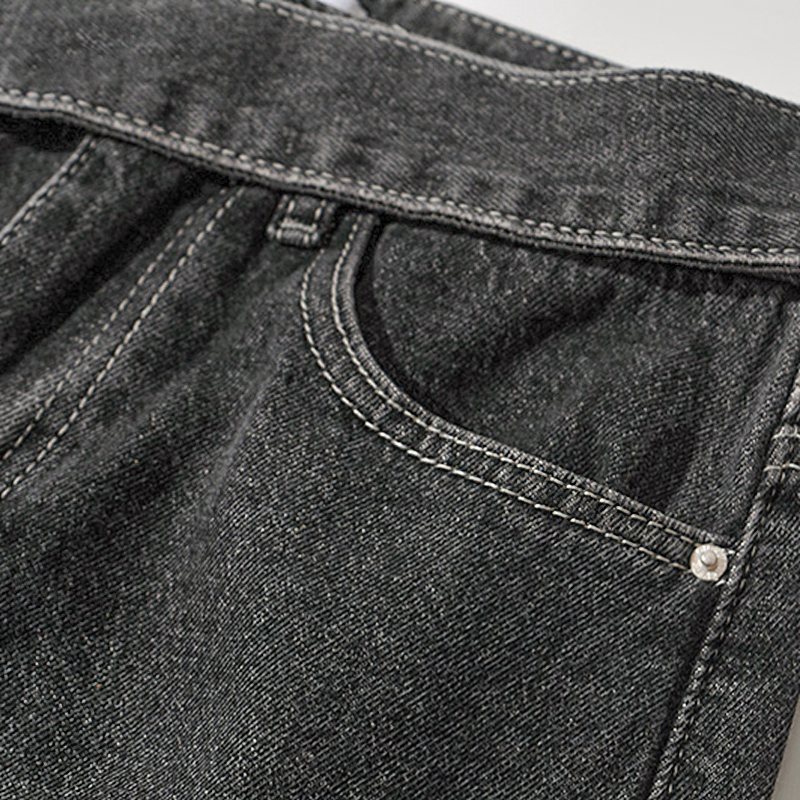 Close-up of high-waisted fashion women's long loose jeans with belt and pockets, showcasing cool denim texture and design.