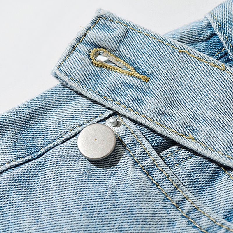 Close-up of soft fabric and button detail on women's cool denim pants with belt loops, showcasing trendy design.