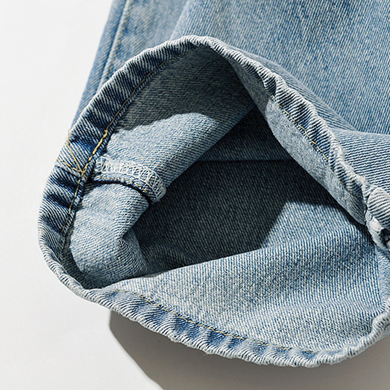 Close-up of the cuff of women's trendy long denim jeans with soft fabric and detailed stitching.