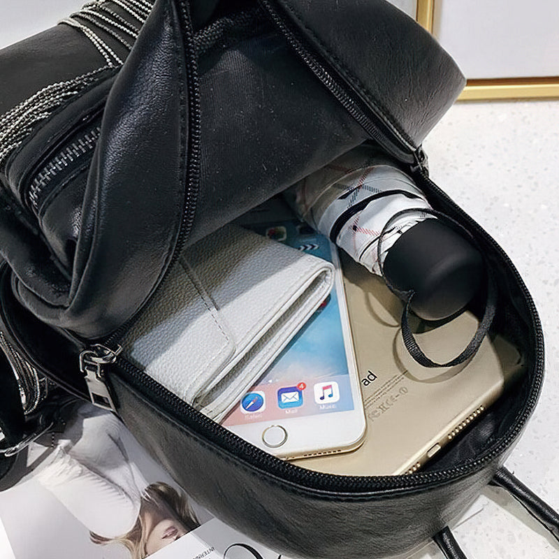 Inside view of a mini black backpack with phone, wallet, and bottle, showcasing its stylish design and functionality.
