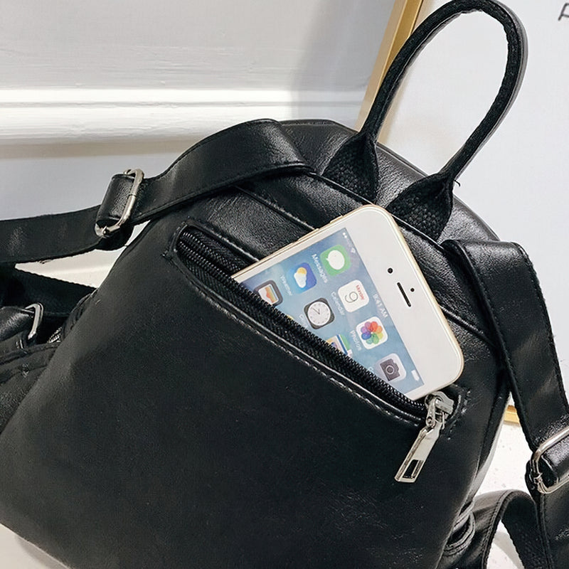 Mini black backpack with a smartphone in the zipped pocket, stylish and functional for casual outings.