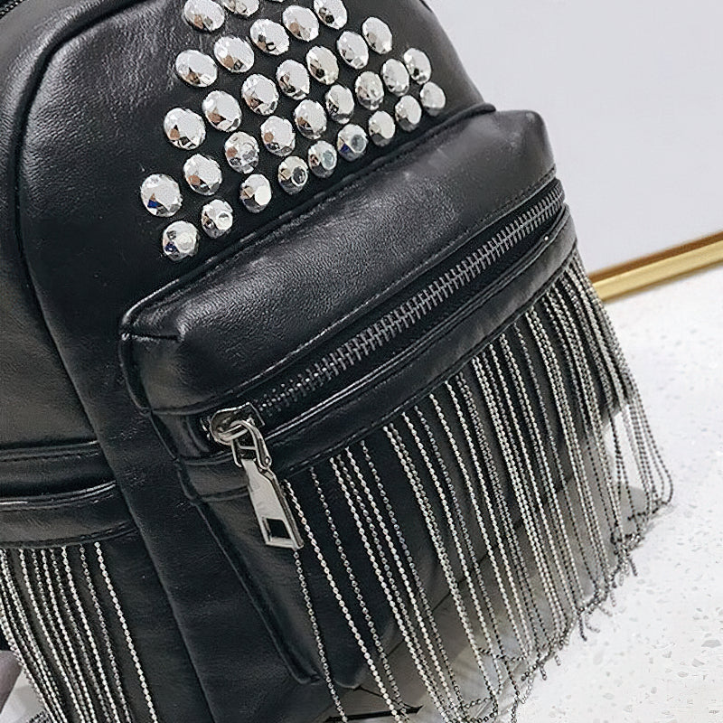 Close-up of a stylish black mini backpack with rivets and fringe detailing, perfect for casual outings.
