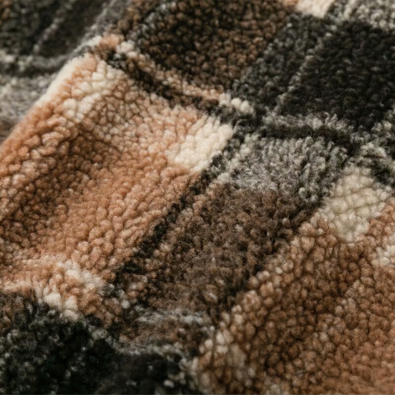 Close-up of cozy plaid lamb wool fabric in warm earthy tones, perfect for stylish women's jackets.