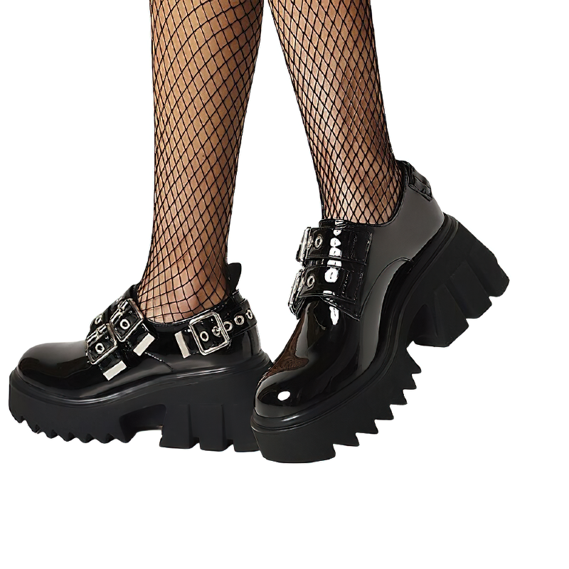 Women's black PU leather loafers with metal buckles, styled with fishnet tights for a gothic look.