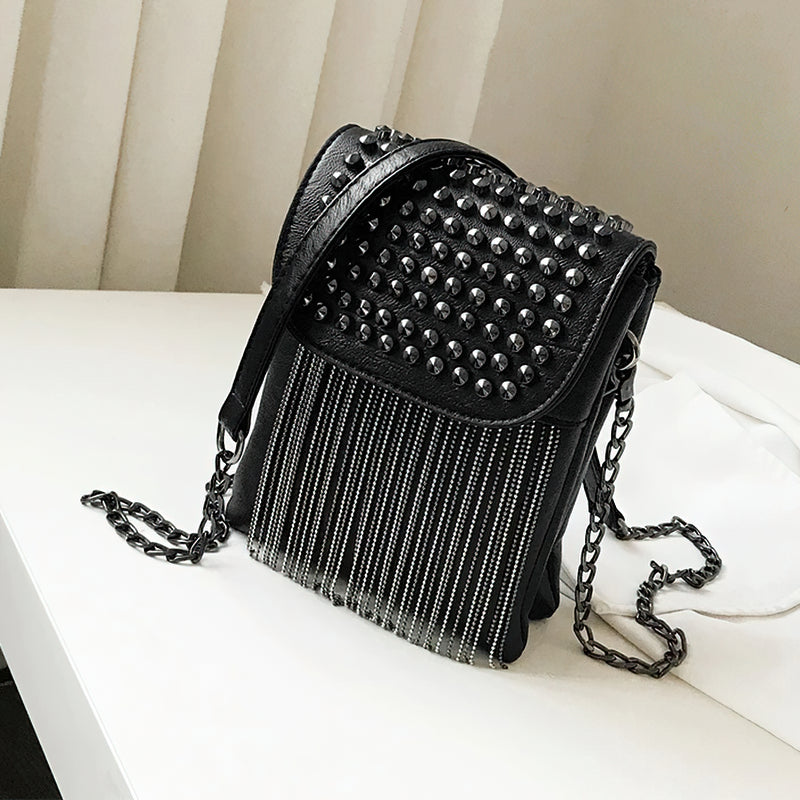 Trendy women's shoulder bag with decorative chain, fringe, and studs in black PU leather.