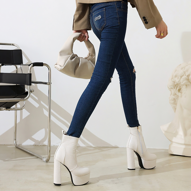 Fashionable woman in trendy square high heel shoes with crocodile print, paired with stylish jeans and a chic bag.