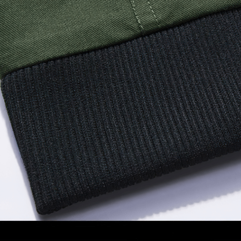 Close-up of a men's military jacket hem showing a green fabric and textured black ribbed cuff.