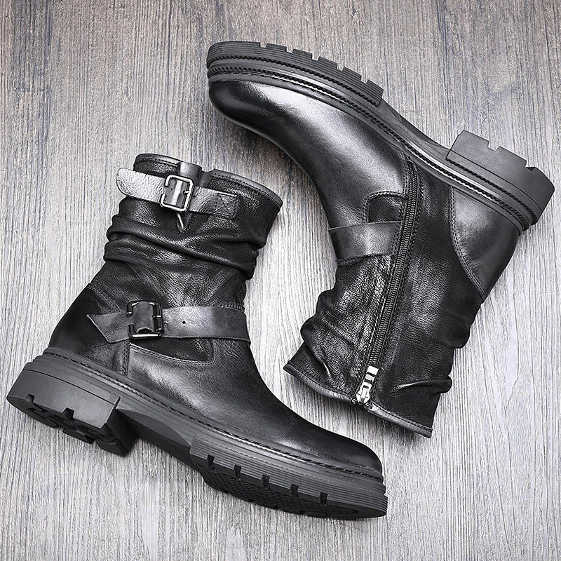Stylish black men's mid-calf leather boots with buckle detail and zipper on a wooden surface.