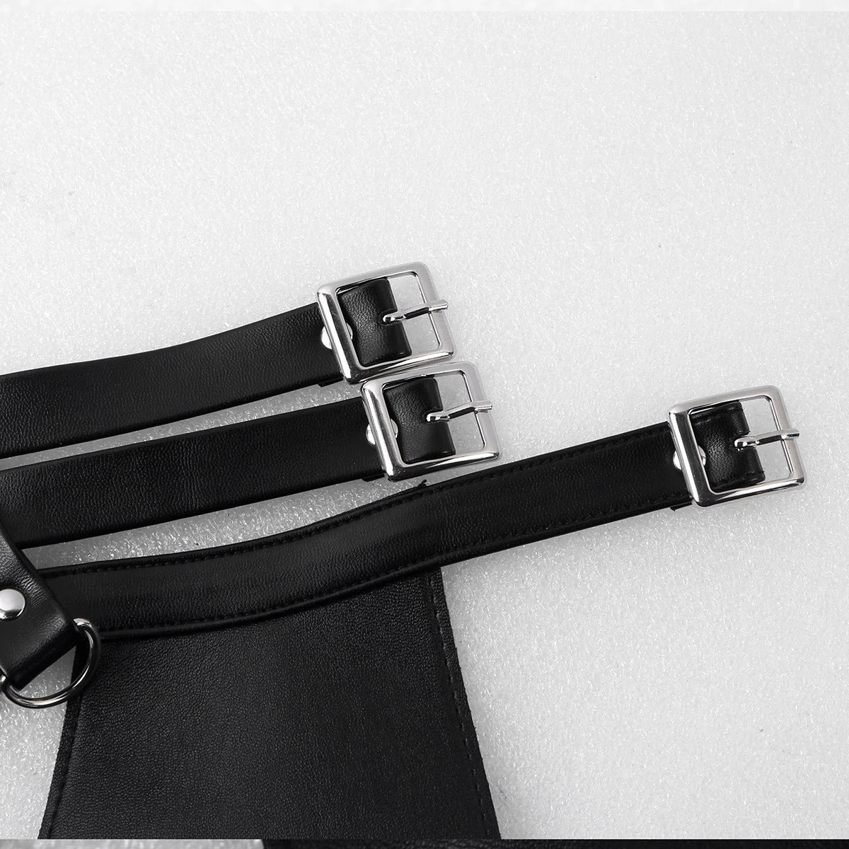 Close-up of adjustable straps on a faux leather chest harness with silver buckles, showcasing comfort and style.