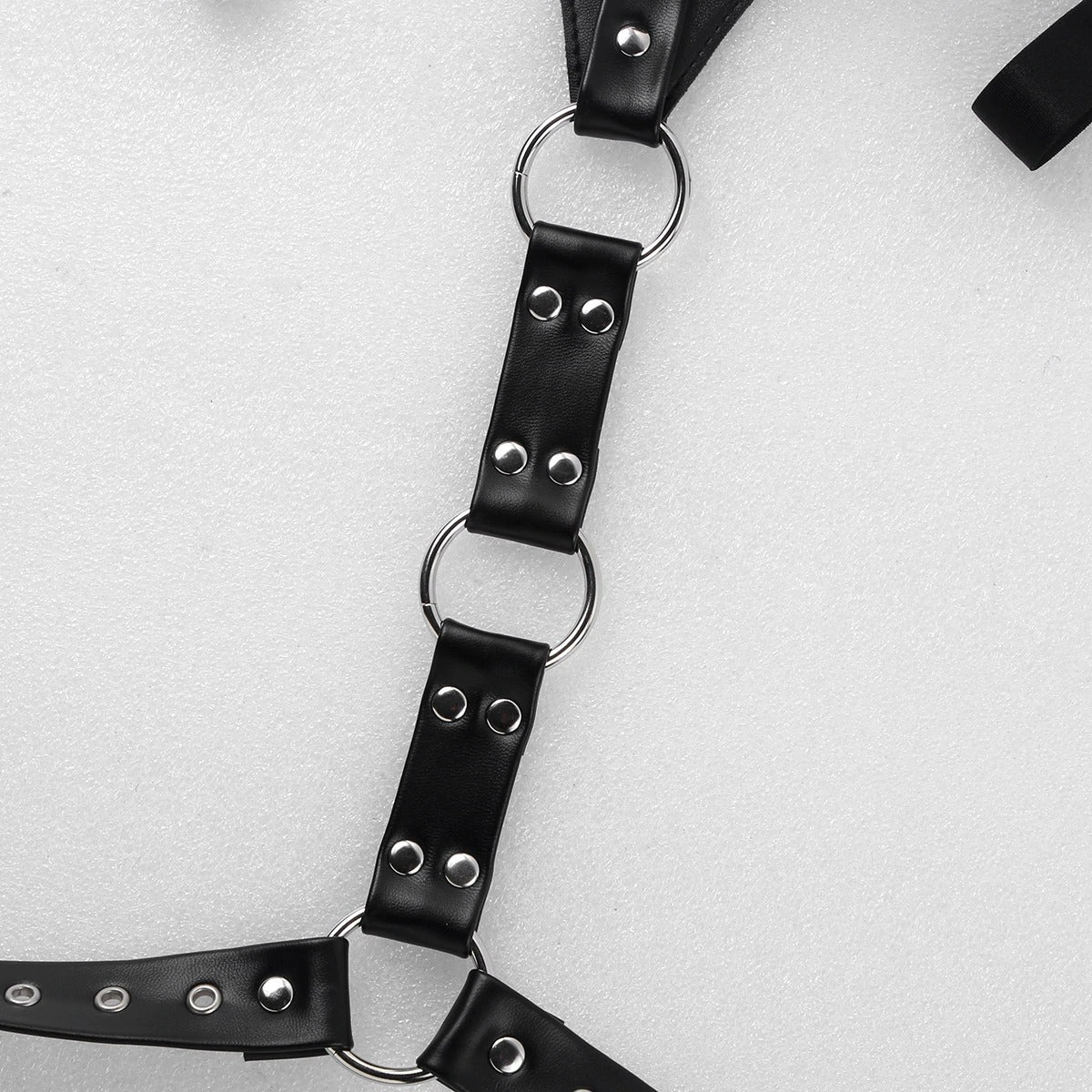 Close-up of a punk style faux leather body chest harness with silver metal rings.