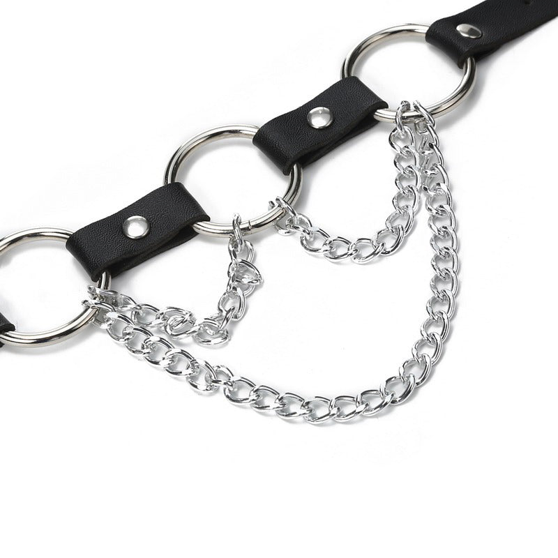 Close-up of a faux leather body harness with silver metal chain detailing for women.