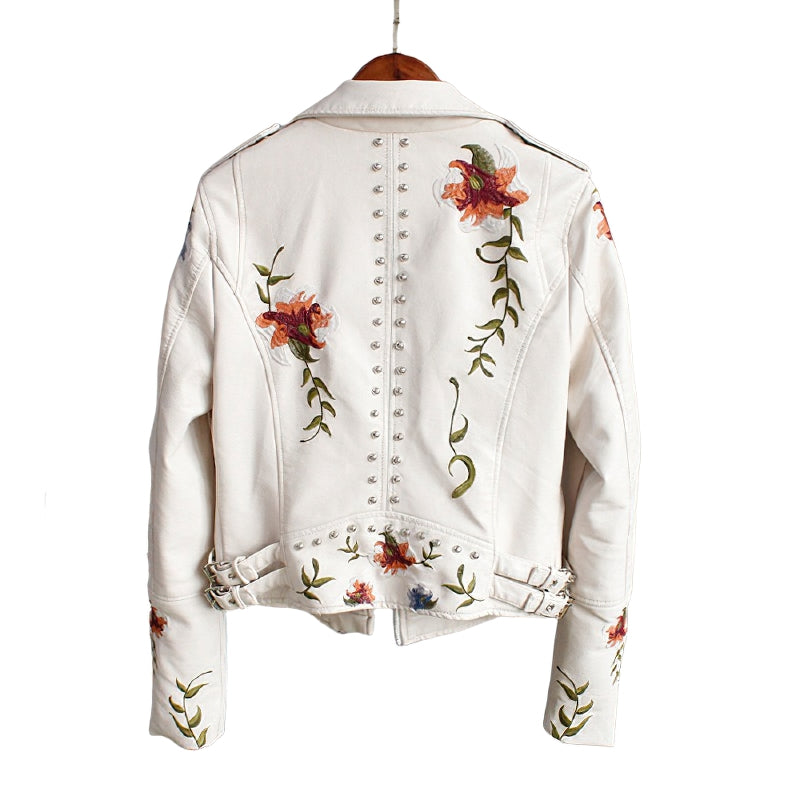 White faux leather women's motorcycle jacket with floral embroidery and studded detailing on the back.