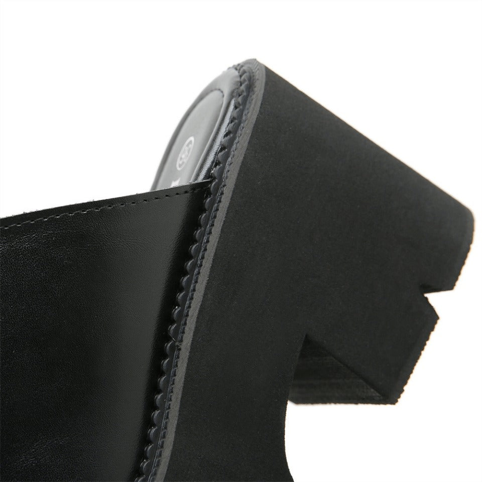 Close-up of black leather platform sandal showing elegant open toe design and stylish heel detail.