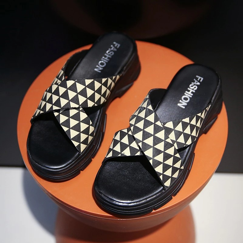 Chic women's black and beige triangular patterned sandals on an orange pedestal, perfect for an alternative aesthetic.
