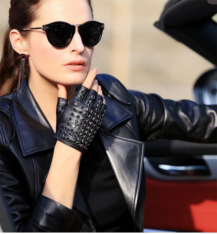 Stylish woman in leather jacket and semi-finger gloves with rhinestones, showcasing punk fashion.